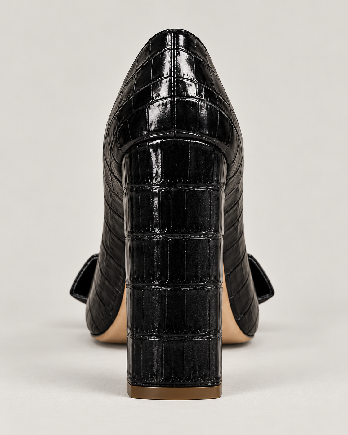 Back view of the black croc-effect pump, showing the tall block heel and gold-tone heel tip.