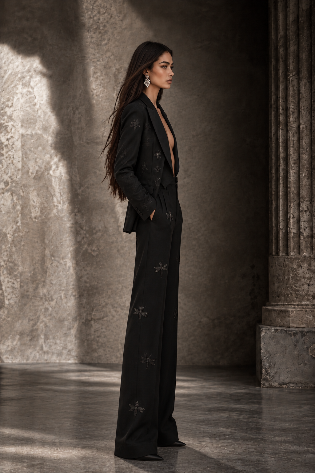 LIGNES D’OMBRE Embroidered Tuxedo Trouser Suit in black, full-length editorial profile against a stone interior.