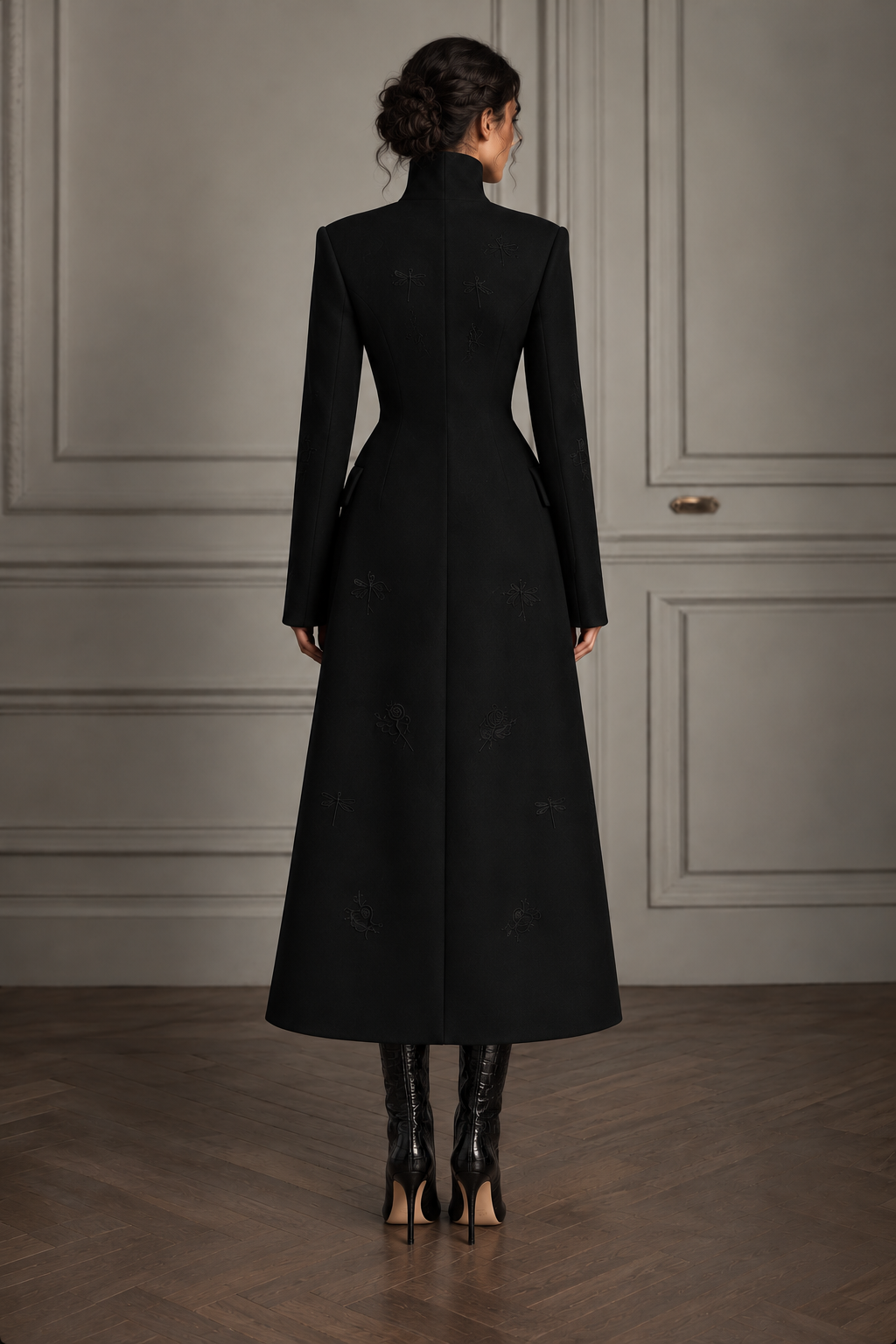 Back view of the black high-collar embroidered A-line coat on a model, showing shaped seams and tonal motifs.