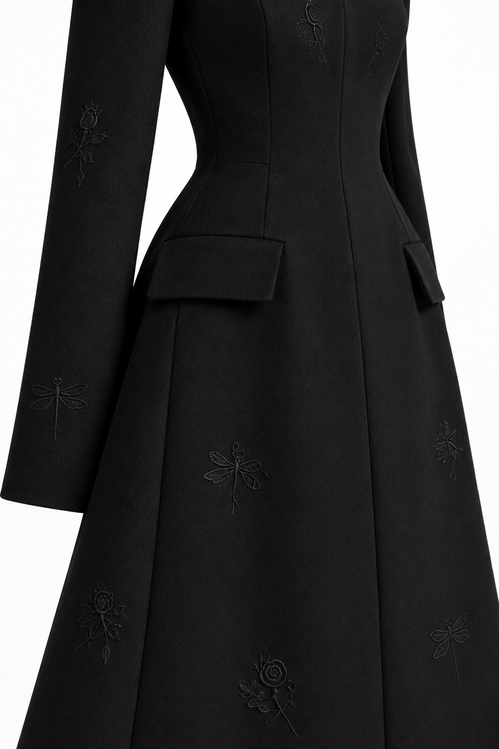 Close-up of the coat’s flap pocket, tailored waist and tonal rose and dragonfly embroidery on the flared skirt.