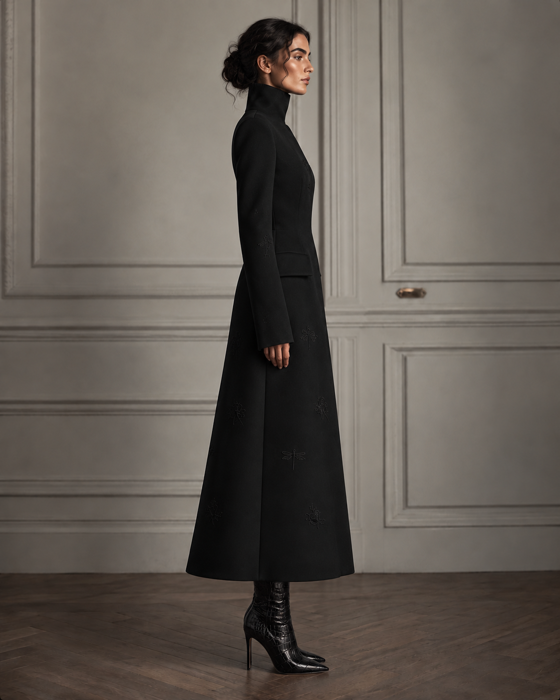 Side view of the black high-collar embroidered A-line coat, showing the fitted waist and long flared hem.
